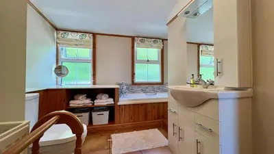 a kitchen with a sink and a tub and two windows at Below the castle at Snowdonia in Harlech
