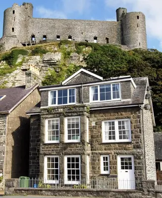 a large stone house with a castle in the background at Below the castle at Snowdonia in Harlech