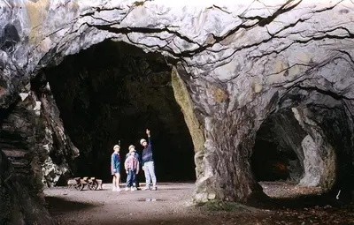 three people and a dog walking through a cave at Below the castle at Snowdonia in Harlech