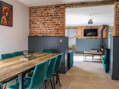 a dining room with a wooden table and green chairs at Threshers Barn in Oswestry