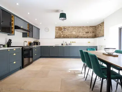 a kitchen with a wooden table and green chairs at Threshers Barn in Oswestry