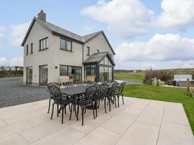 a patio with a table and chairs in front of a house at Rhandir Hen in Aberystwyth