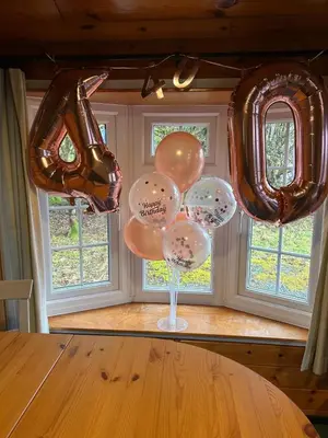a bunch of balloons are hanging above a table at 345 Ida's Cabin in Trawsfynydd