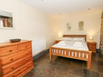 a bedroom with a bed and a wooden dresser at Llwyngwinau Isaf Barn in Tregaron