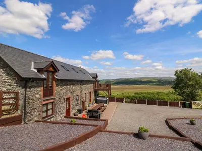 an external view of a stone house with a patio at Llwyngwinau Isaf Barn in Tregaron
