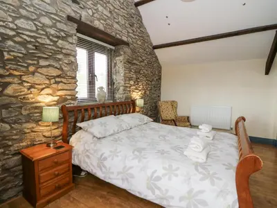 a bedroom with a bed and a stone wall at Llwyngwinau Isaf Barn in Tregaron