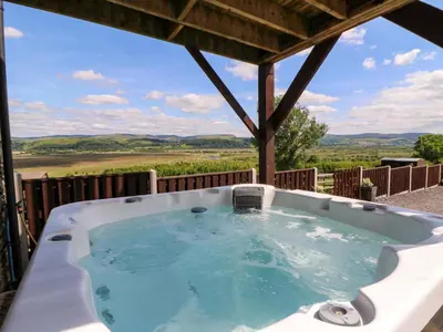 a jacuzzi tub on a deck with a view at Llwyngwinau Isaf Barn in Tregaron