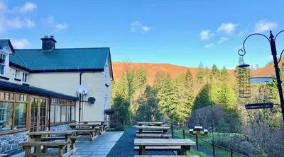 a group of wooden picnic tables outside of a building at Ty Penbont House in Rhayader