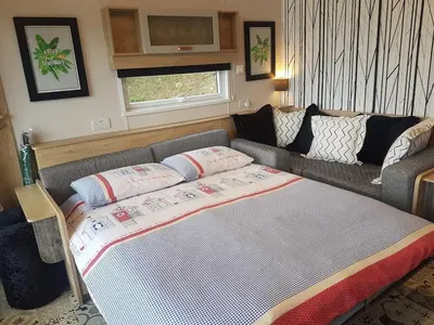 a living room with a couch and a bed at POD2 Family Glamping with seaview & Wi-Fi in Llwyngwril