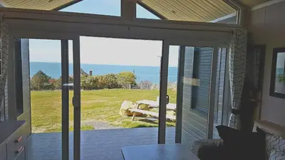 an open patio door with a view of the ocean at POD2 Family Glamping with seaview & Wi-Fi in Llwyngwril