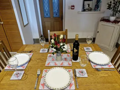 a table with plates and glasses and a bottle of wine at Green Hill ground floor Family Apartment in Barmouth