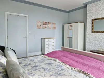 a bedroom with a pink bed and a dresser at Green Hill ground floor Family Apartment in Barmouth