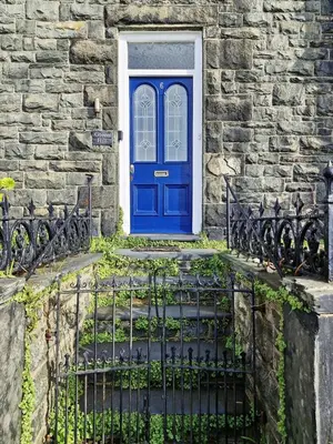a blue door on a stone building with a gate at Green Hill ground floor Family Apartment in Barmouth