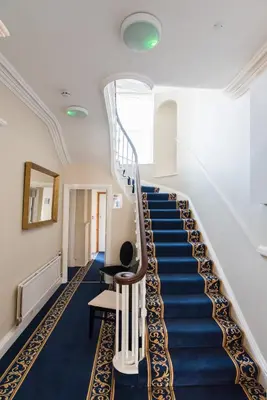 a staircase in a building with a blue carpet at No 46 Marine Terrace in Aberystwyth