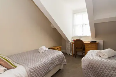 a bedroom with two beds and a desk and a window at No 46 Marine Terrace in Aberystwyth