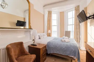 a bedroom with a bed and a chair and a mirror at No 46 Marine Terrace in Aberystwyth