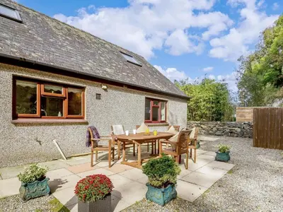a patio with a wooden table and chairs in front of a house at Tan-y-Graig at Snowdonia in Harlech