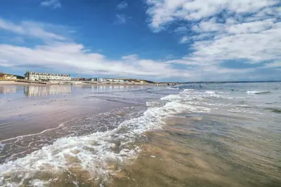 a beach with the ocean and buildings in the background at 2 Bed in Rhoslefain oc-i30763 in Llangelynin