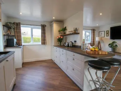 a kitchen with a counter and stools in it at Blockley Lodge in Church Stretton