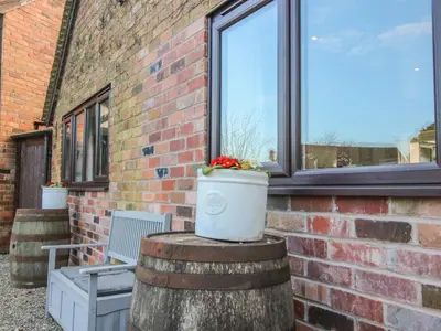 a brick building with a window and a pot of flowers at Blockley Lodge in Church Stretton
