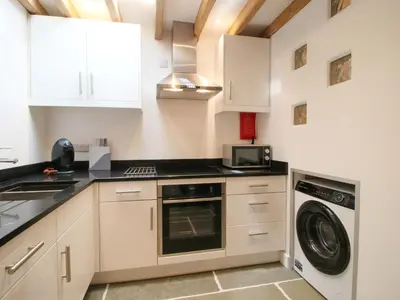 a kitchen with white cabinets and a washer and dryer at The Hideaway in Bishops Castle