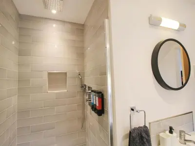 a bathroom with a shower with a mirror and a sink at The Hideaway in Bishops Castle
