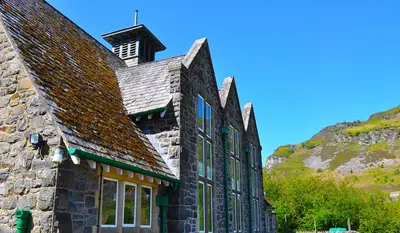 a stone building with a clock tower on top of it at Elan Valley Lodge in Llanwrthwl