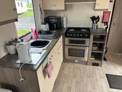 a small kitchen with a stove and a sink at Ocean Breeze Hideaway 2 Bed Pet Friendly Static Caravan In Clarach Bay in Aberystwyth