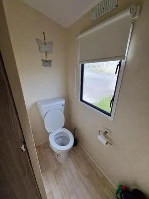a small bathroom with a toilet and a window at Ocean Breeze Hideaway 2 Bed Pet Friendly Static Caravan In Clarach Bay in Aberystwyth