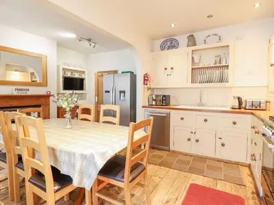 a kitchen with a table and chairs and a refrigerator at Mor Iwerddon in Barmouth