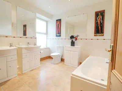 a bathroom with two sinks and a toilet and a tub at Mor Iwerddon in Barmouth