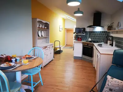 a kitchen with a table and chairs and a kitchen with a counter at Relaxing Coastal Retreat for 2 Hot Tub Log Fire in Tywyn