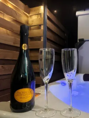 a bottle of wine and two glasses on a table at Relaxing Coastal Retreat for 2 Hot Tub Log Fire in Tywyn