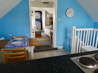 a kitchen with a table and a clock on the wall at The Loft - Shrewsbury in Shrewsbury