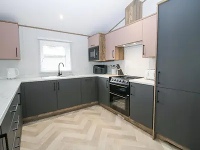 a kitchen with green cabinets and a wooden floor at Peony in Leominster