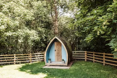 a small blue shed with a door in the grass at Shepherd's Hut at Lythwood, Near Shrewsbury in Baystonhill