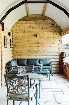 a patio with benches and a table and chairs at Shepherd's Hut at Lythwood, Near Shrewsbury in Baystonhill