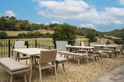 a row of picnic tables and chairs with a view at Stud Farm House in Bleddfa