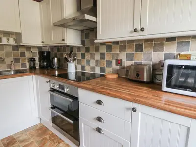 a kitchen with white cabinets and a counter with a microwave at Cantref House Top Floor in Brecon