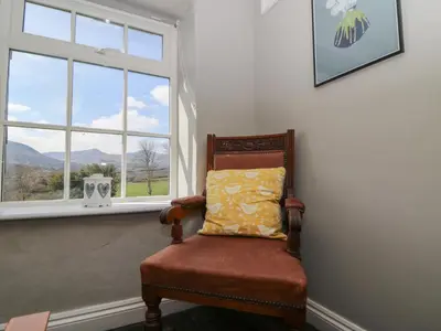 a chair with a pillow sitting in front of a window at Cantref House Top Floor in Brecon
