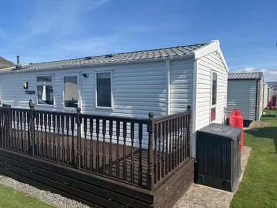 a mobile home with a fence and a fire hydrant at Sea Breeze Retreat 2 Bedroom Pet Friendly Caravan in Clarach Bay in Aberystwyth