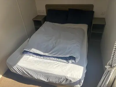 a small bed in a room with white sheets at Sea Breeze Retreat 2 Bedroom Pet Friendly Caravan in Clarach Bay in Aberystwyth
