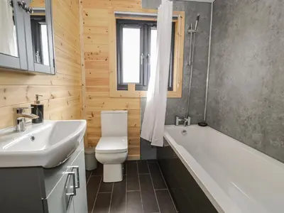 a bathroom with a tub and a toilet and a sink at Sunset Lodge 5 in Llanbedr