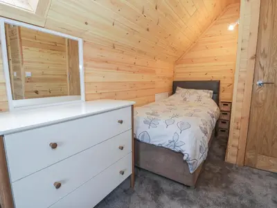 a bedroom with a bed and a dresser in a cabin at Sunset Lodge 5 in Llanbedr