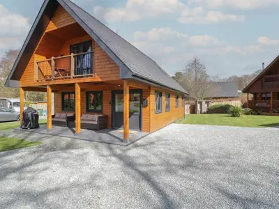 a large wooden house with a gambrel roof at Sunset Lodge 5 in Llanbedr