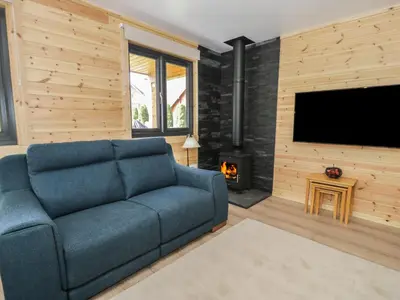 a living room with a blue couch and a fireplace at Sunset Lodge 5 in Llanbedr