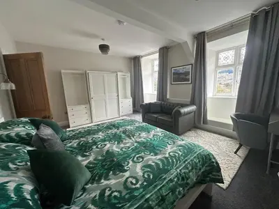 a bedroom with a bed and a chair and window at Cil-y-Coed in Dolgellau