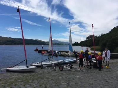 a group of people standing around sailboats on a lake at Cosy cottage in Snowdonia hamlet in Frongoch
