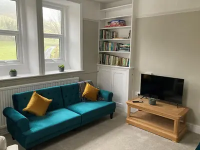 a living room with a blue couch and a tv at Tyn-Y-Berth Sleeps 27 luxury group accommodation in Tal-y-llyn