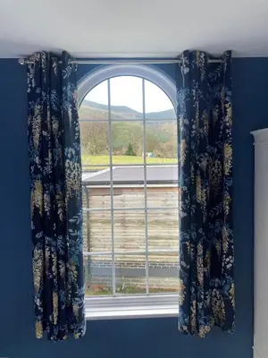 a window with blue curtains in a room at Tyn-Y-Berth Sleeps 27 luxury group accommodation in Tal-y-llyn